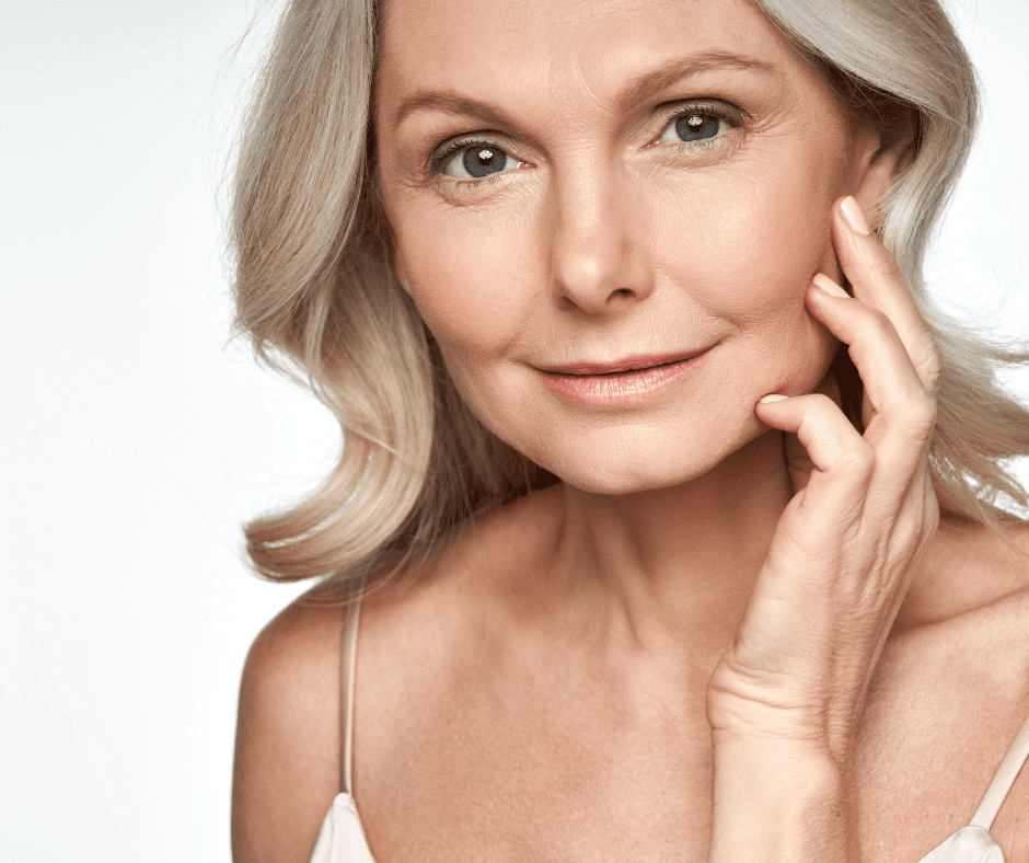 An older woman admiring her face after a Dermal Filler.